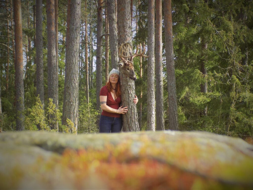 Kuppari-Hanna metsässä halaamassa puuta.