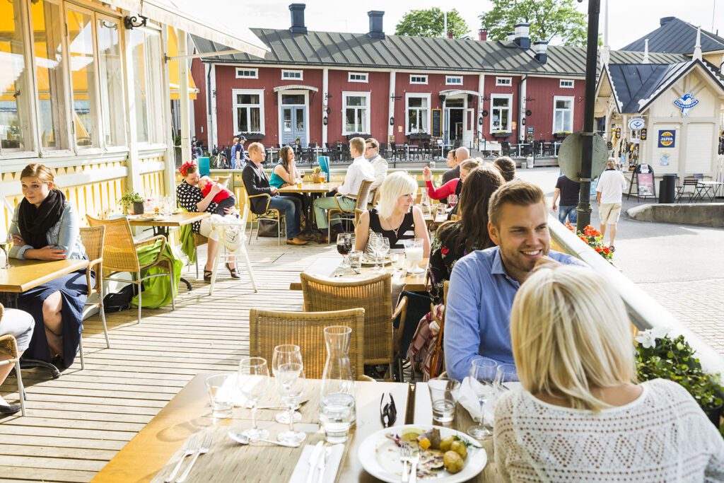 Snickari-ravintolan kesäinen terassi, jossa iloisia asiakkaita ruokailemassa ja seurustelemassa.