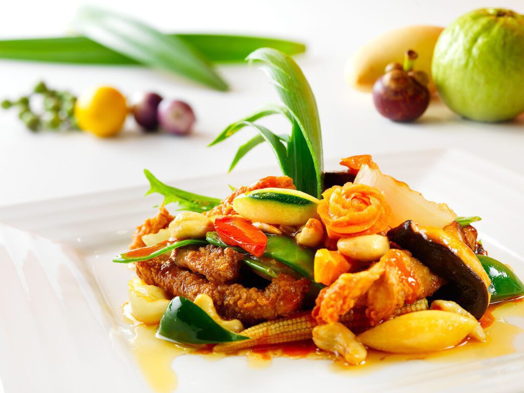 Thai Garden ravintolan annoskuva, jossa lihaa, minimaissia ja koristeellisesti leikattuja vihanneksia.