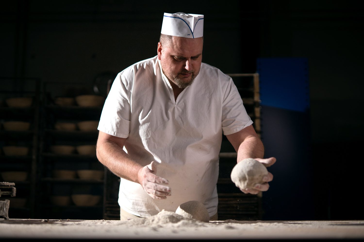 Leipuri leipoo jauhoisilla käsillä taikinapalloa.