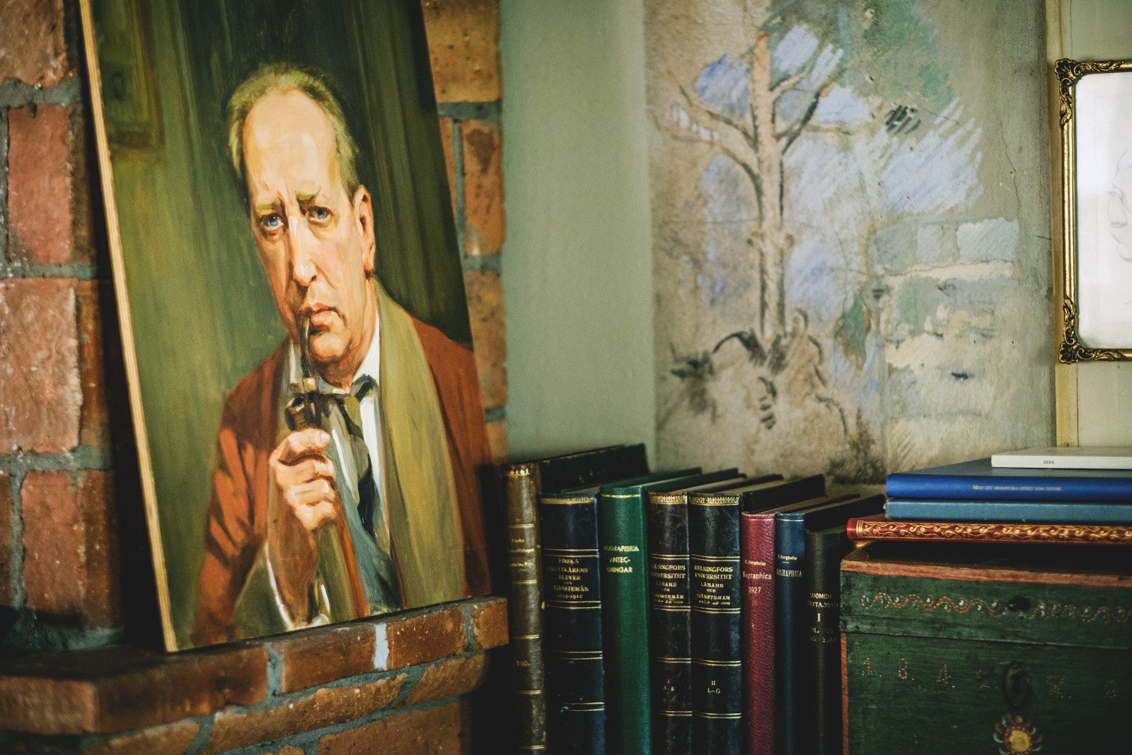 Casa Haartmannin huoneen nurkka, jossa näkyy maalaus miehestä ja rivi monivärisiä kirjoja.
