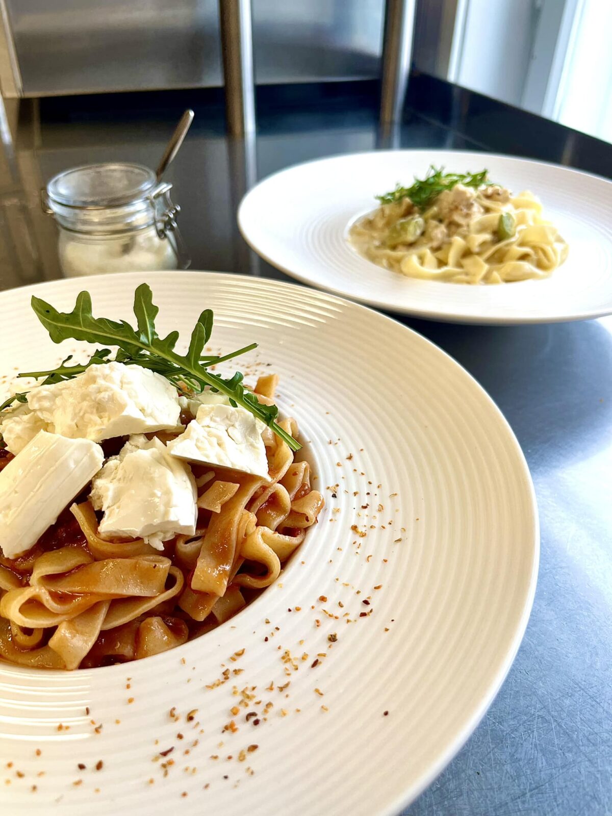 Hasta la Pasta -ravintolan pasta-annoksia valkoisilla lautasilla.