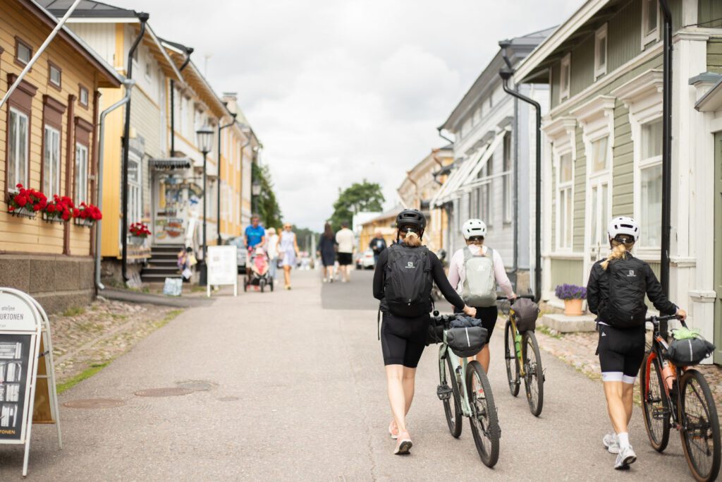 Pyöräilijöitä ja kävelijöitä Naantalin Vanhankaupungin kadulla kesäpäivänä.