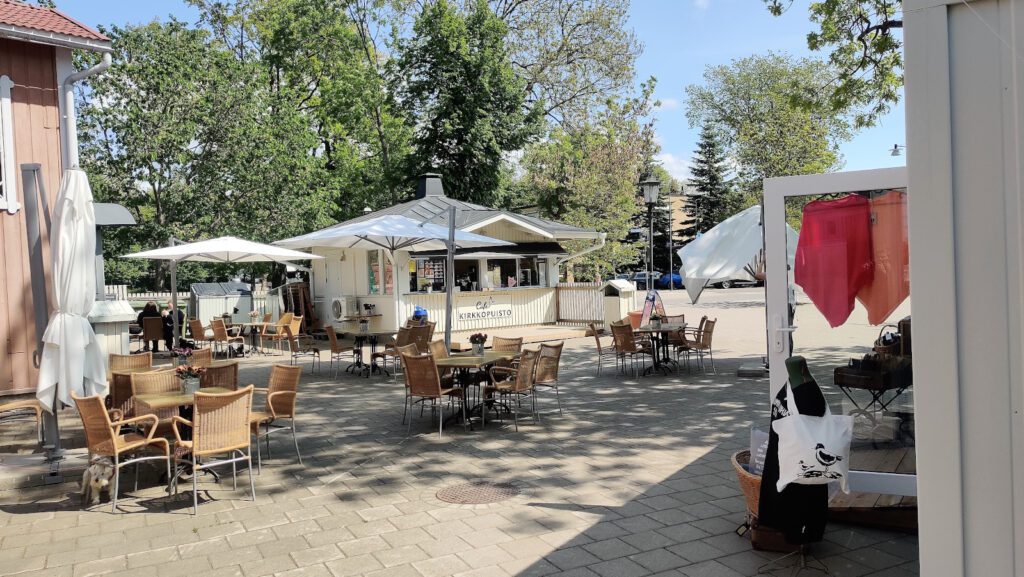 Naantalin Kesäshopin vieressä sijaitseva jäätelökioski-kahvila sekä pöytiä ja tuoleja viihtyisällä sisäpihalla.