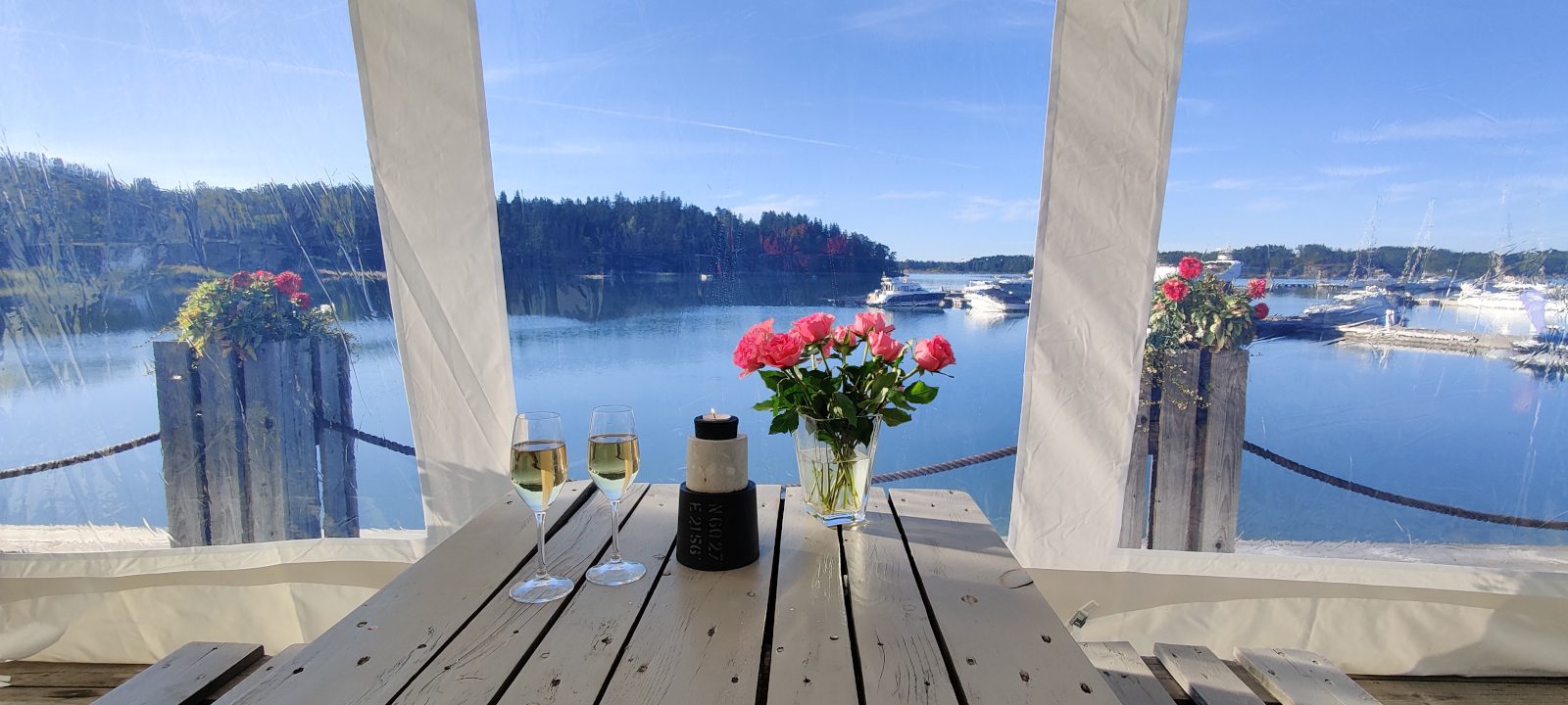 Merellinen näköala Kultaranta Marinan terassilta, jonka pöydällä viinilasit, kynttilä sekä kukkia.
