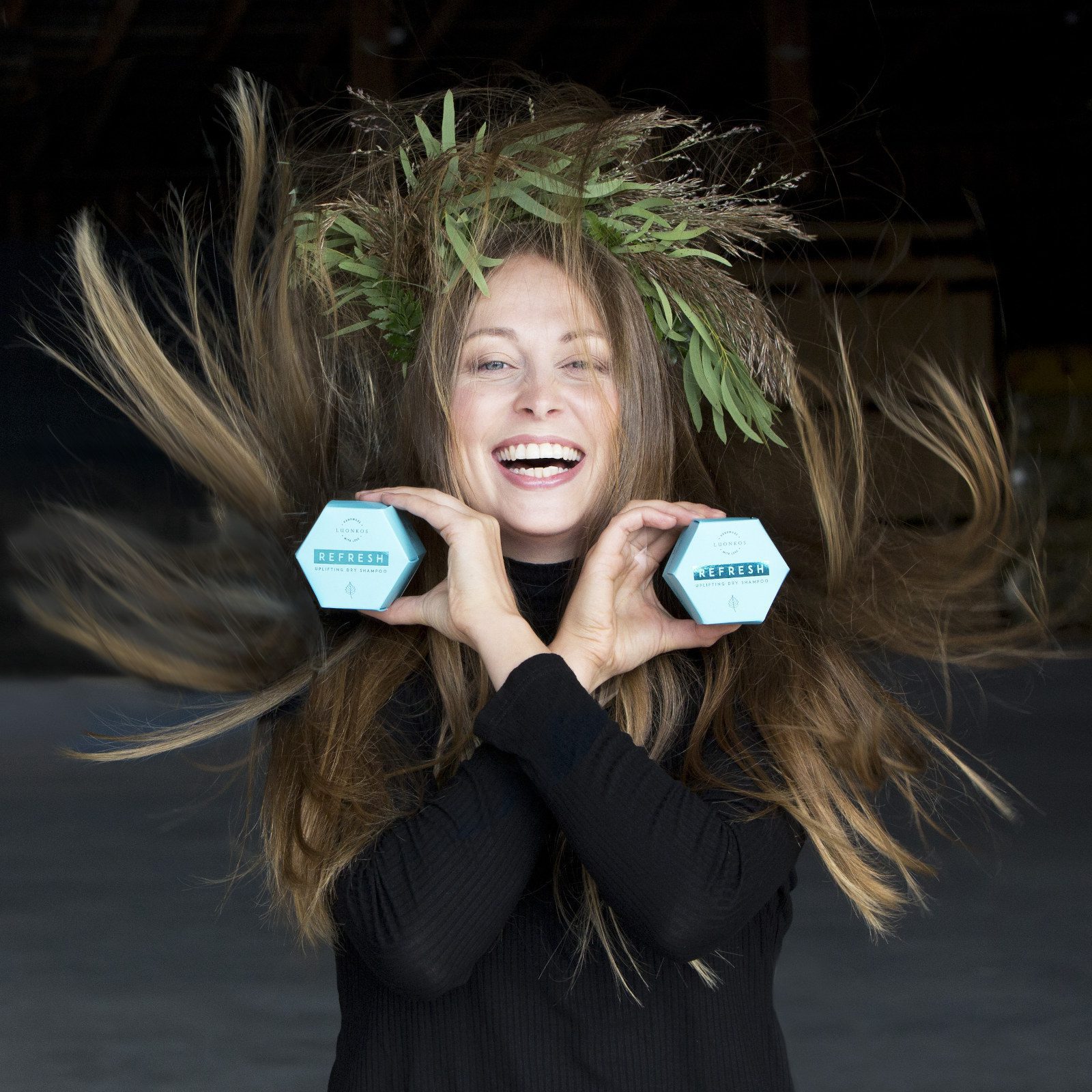 Nauravainen nainen pitää käsissään kahta sinistä Luonkos luonnonkosmetiikan puhdistuskakkupakkausta.