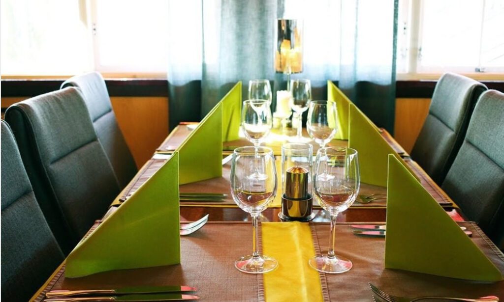Ravintola Trapin katettu pöytä, jossa viinilasit ja vihreät servetit.