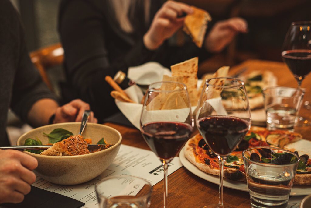 Rucola Bistron ravintolapöytä, jolla italailaisia annoksia ja punaviinilasit.