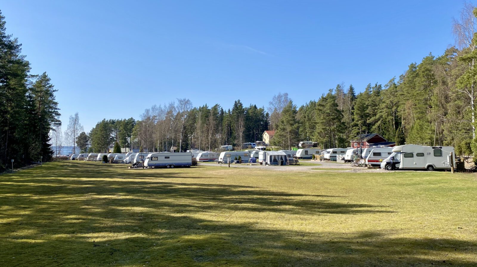 Salorannan leirintäalueella olevia matkailuautoja ja -vaunuja paikoillaan. Taustalla näkyy kaunis luonnonläheinen maisema ja meri.