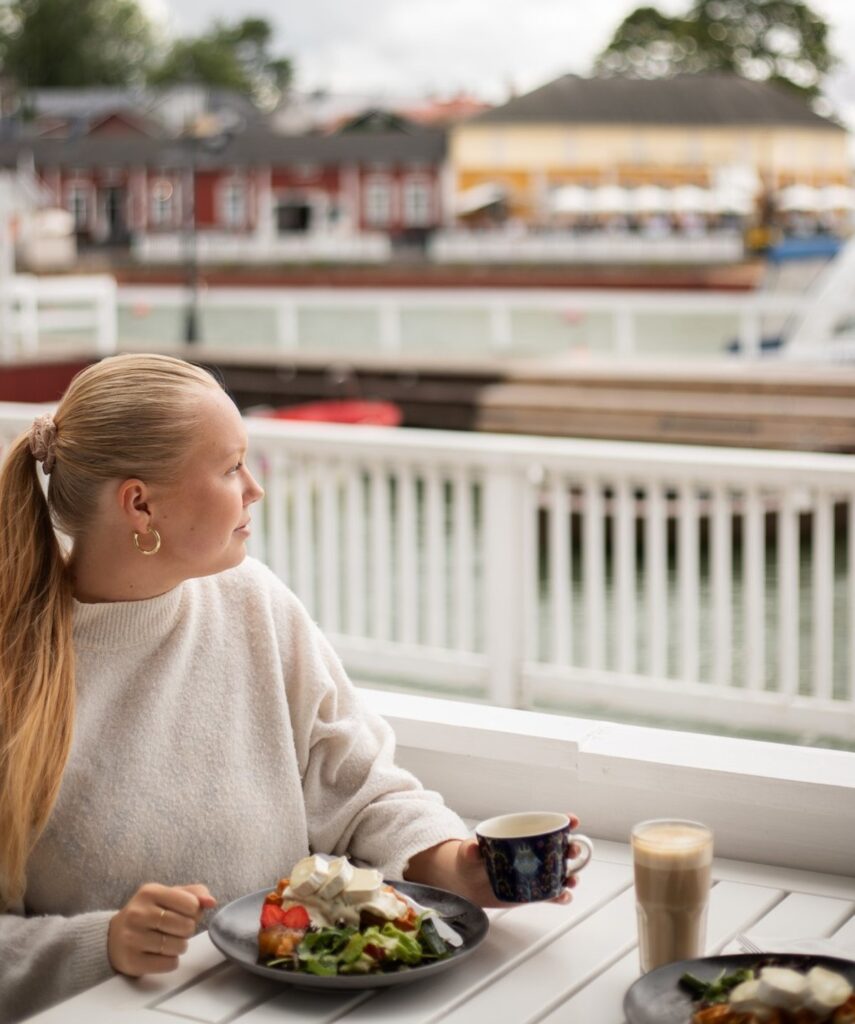 Nainen syömässä vohveliannosta Naantalin rannan ravintolan terassilla.