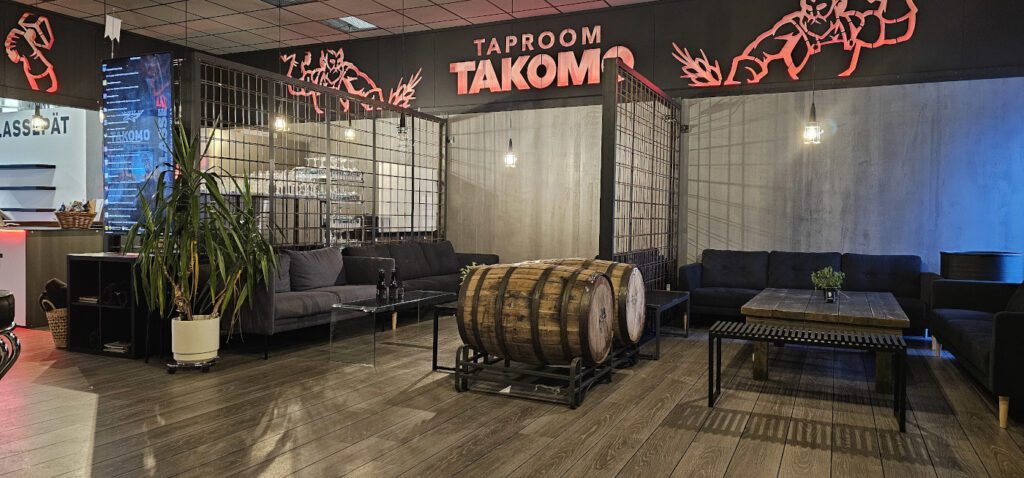 Taproom TAKOMO -anniskeluravintola sisältäpäin kuvattuna. Ravintolassa on rouhea sisustus, oluttynnyreitä sekä tunnelmavalaistus.