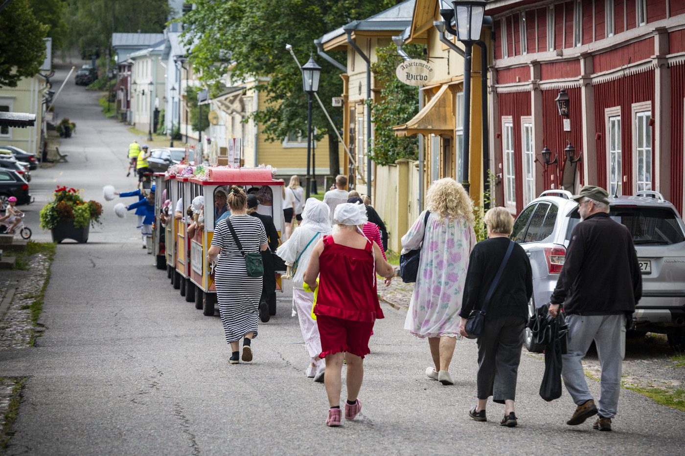 Unikeonpäivän kulkueessa ihmisiä kävelemässä kaupunkijunan perässä Naantalin Vanhassakaupungissa.