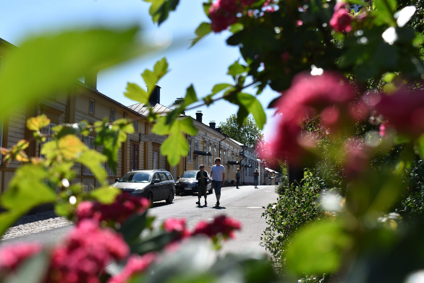 Ihmisiä kävelemässä Naantalin Vanhassakaupungissa kukkien kukkiessa kauniisti.