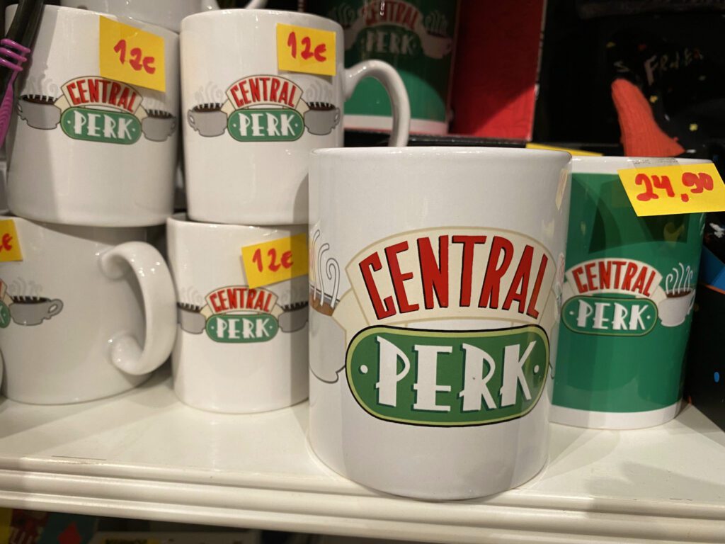 Hyllyllä matkamuistomukeja, jossa Frendit-sarjan Central Perk-kahvilan logo.