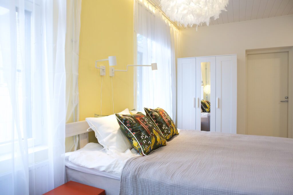 Hotelli Amandiksen raikkaan keltaisella maalattu huone ja kauniisti pedattu sänky.