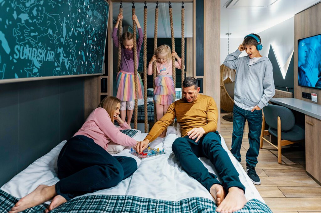 Finnsiriuksen tilava perhehytti, jonka sängyllä perhe pelaa lautapeliä yhdessä.